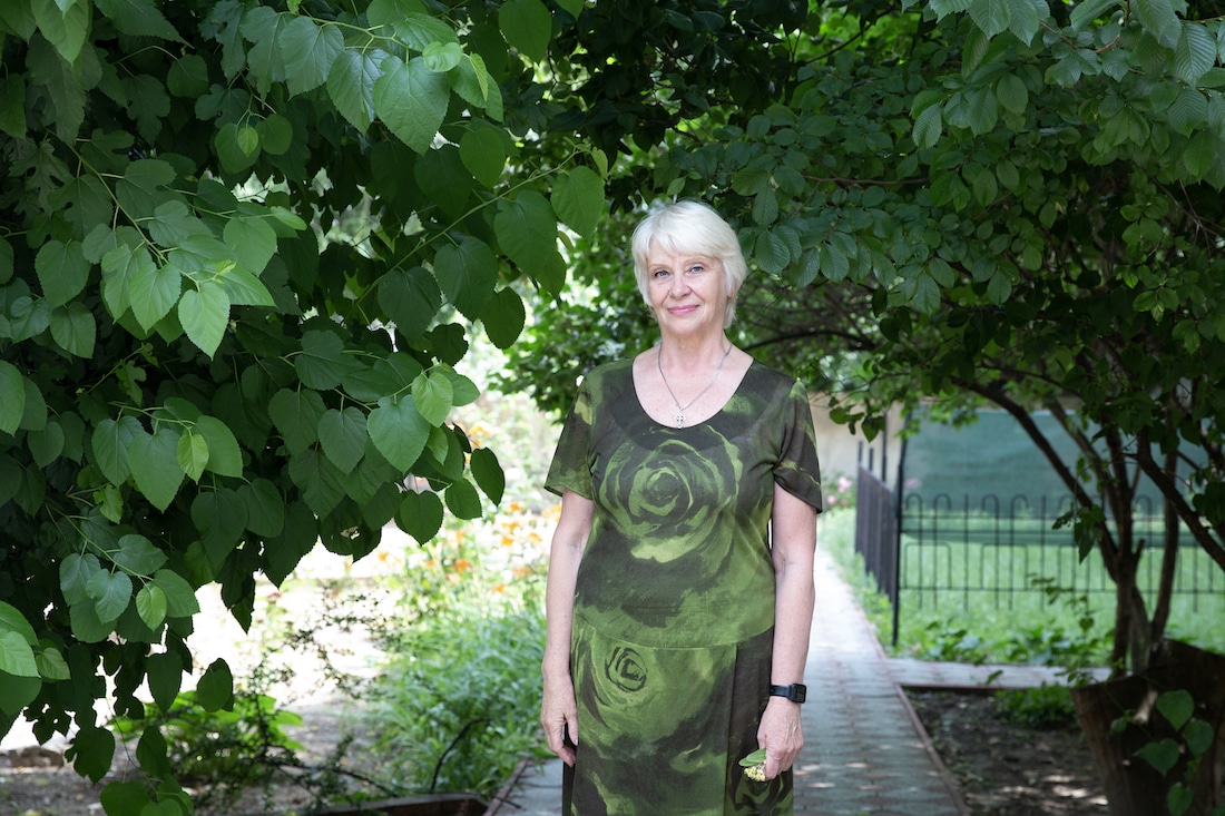 elderly woman stands among trees