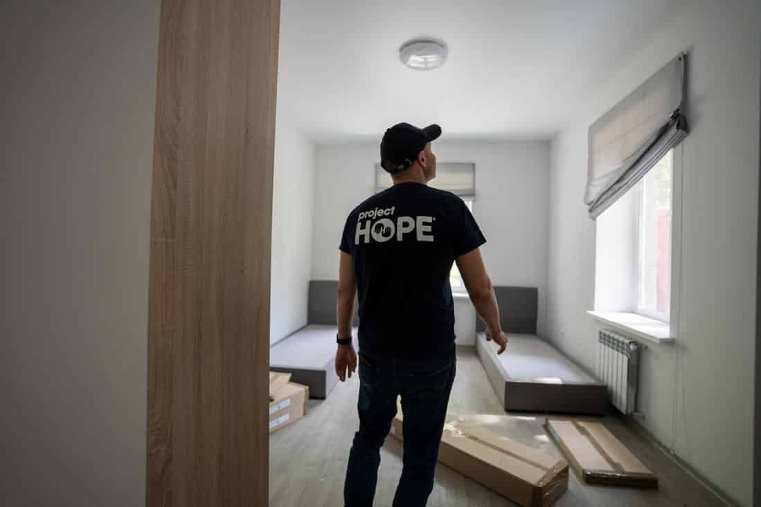 Back of man wearing a Project HOPE shirt looking into a new hospital room.