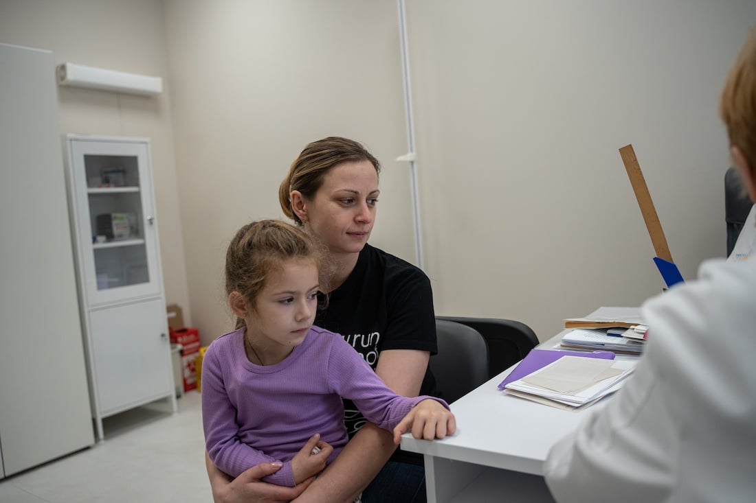 woman holding daughter at doctor's appointment