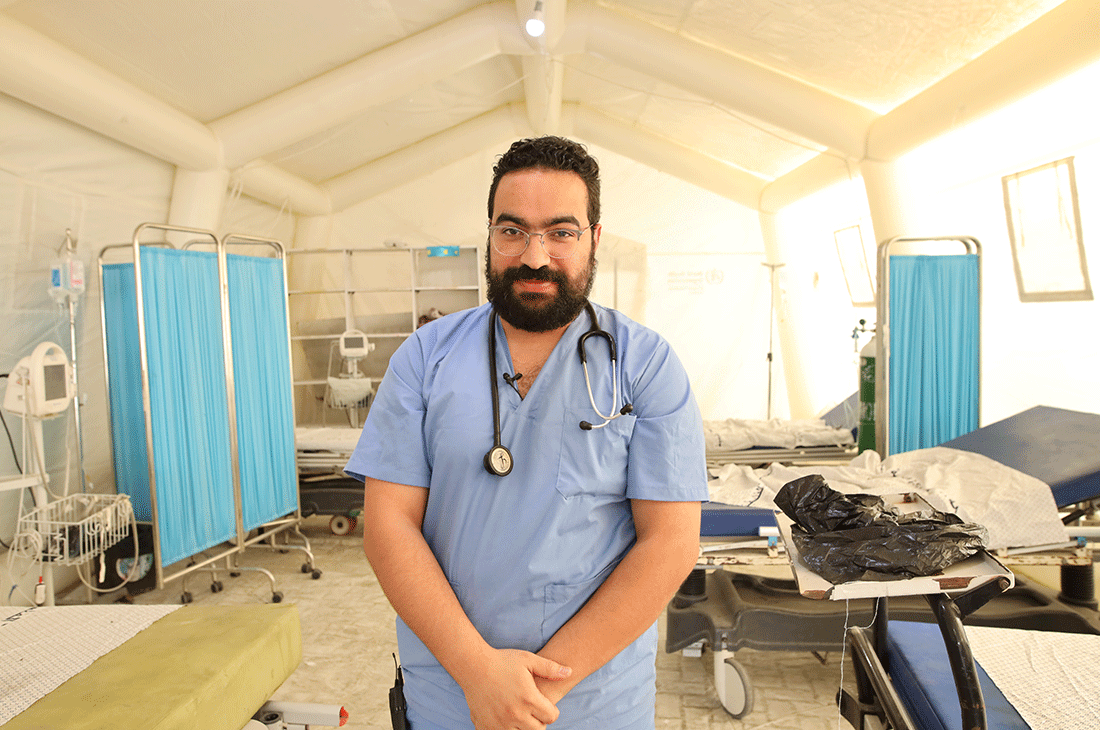 A doctor looks at the camera in a medical tent.