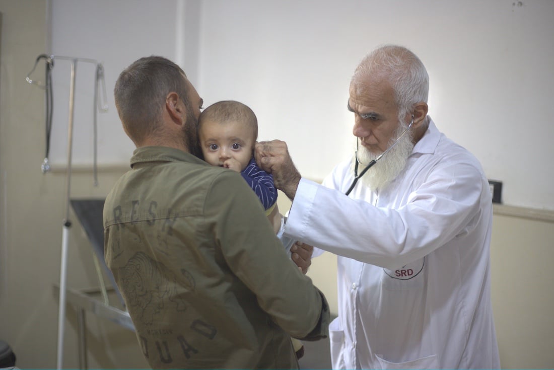 doctor looks into the ear of young boy being held by man