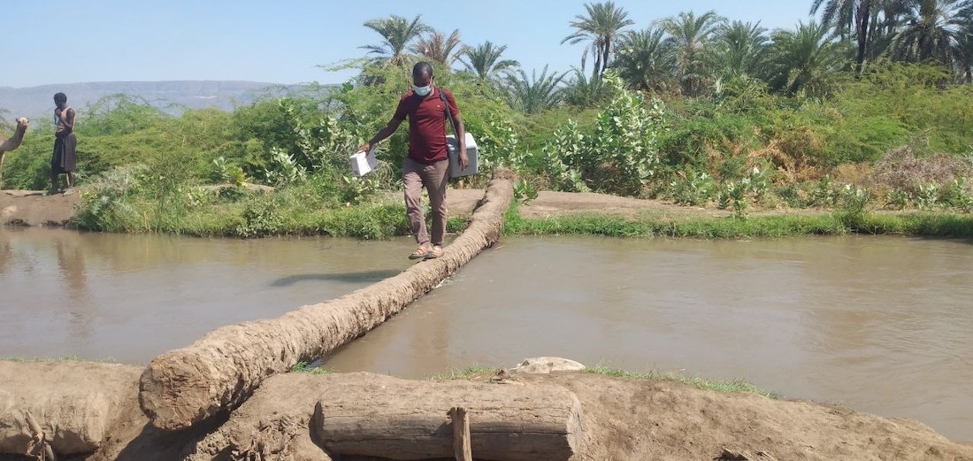 man crossing a river to deliver vaccines