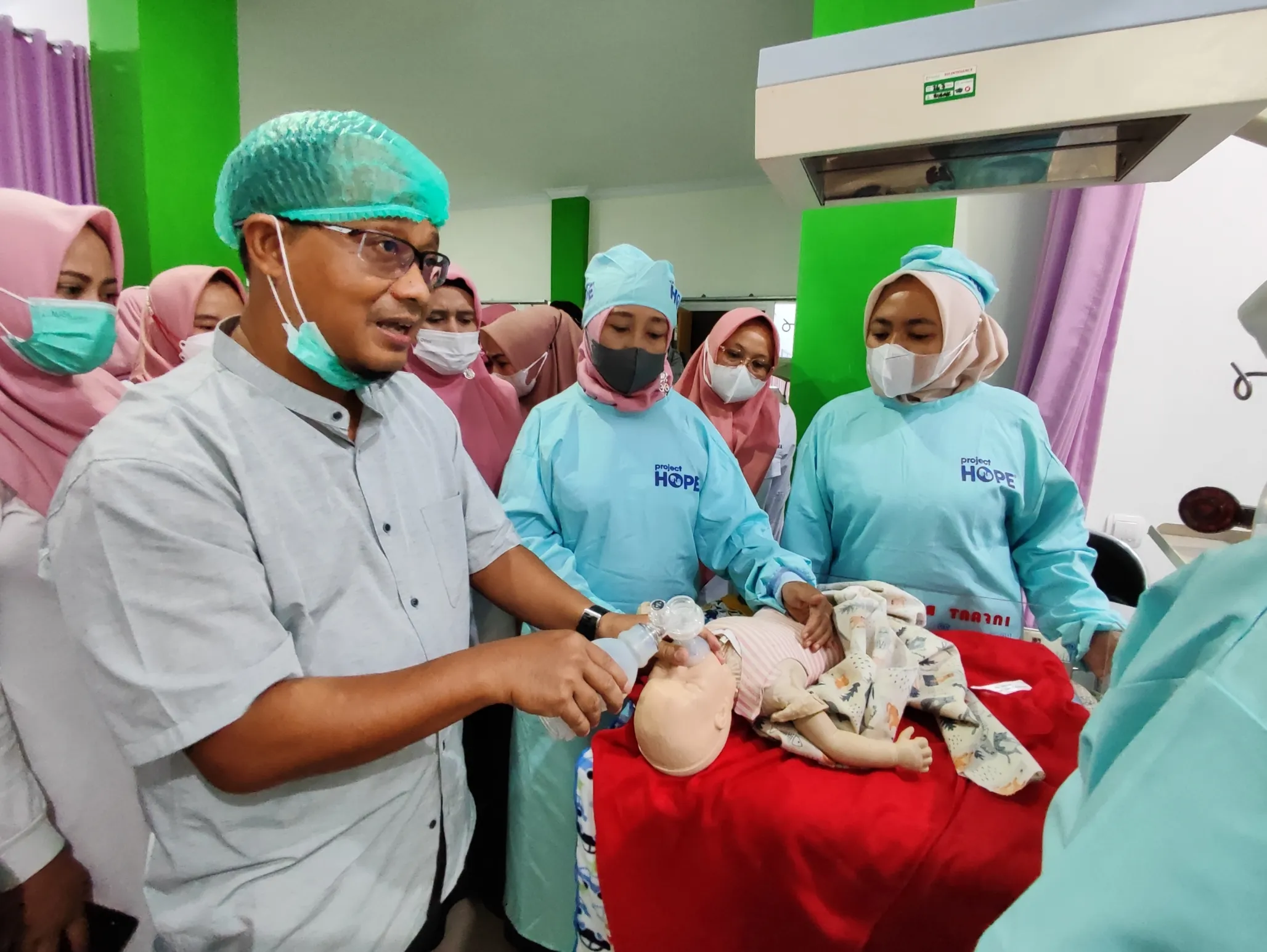 A male doctor teaches medical staff how to pump oxygen into an infant dummy