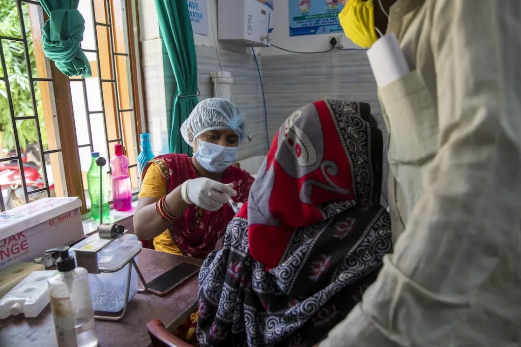 Health care worker gives COVID-19 vaccine in India