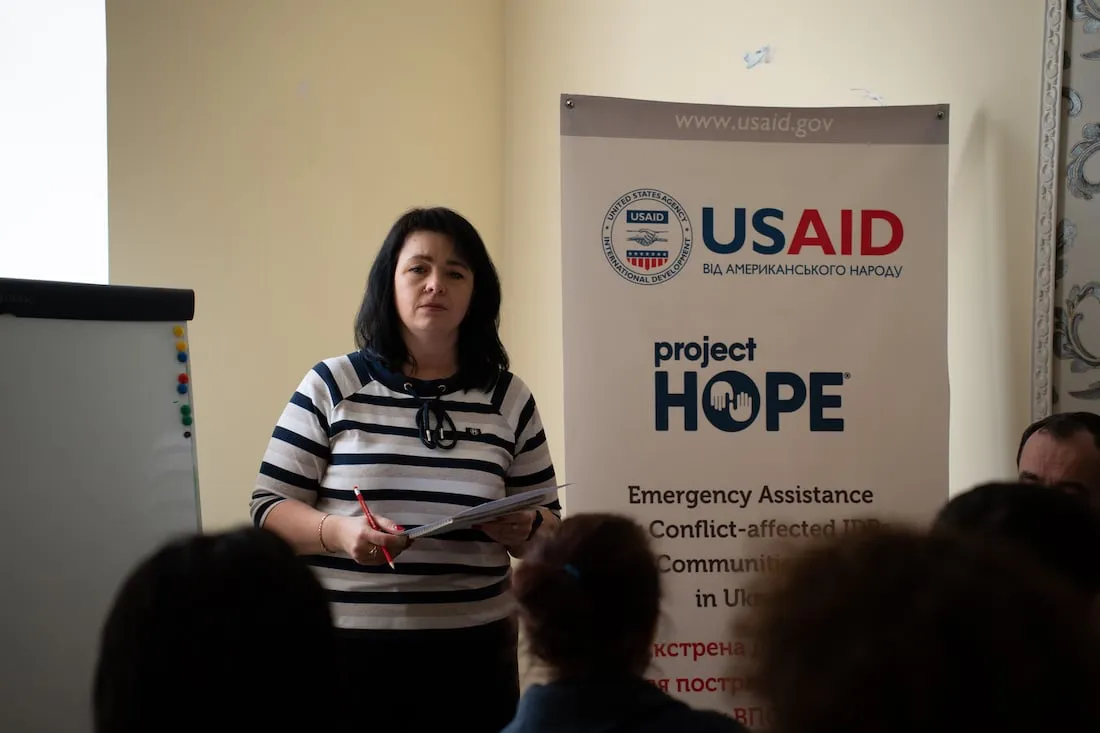 woman in striped navy and white shirt speaking in front of crowd