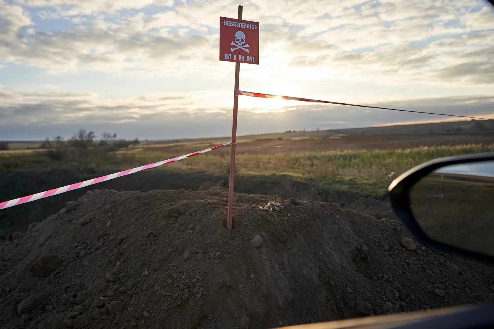 Sunset shot of a mound of dirt with a warning sign above it