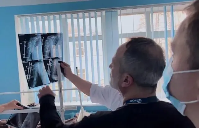 behind the back shot of a man looking at an x-ray