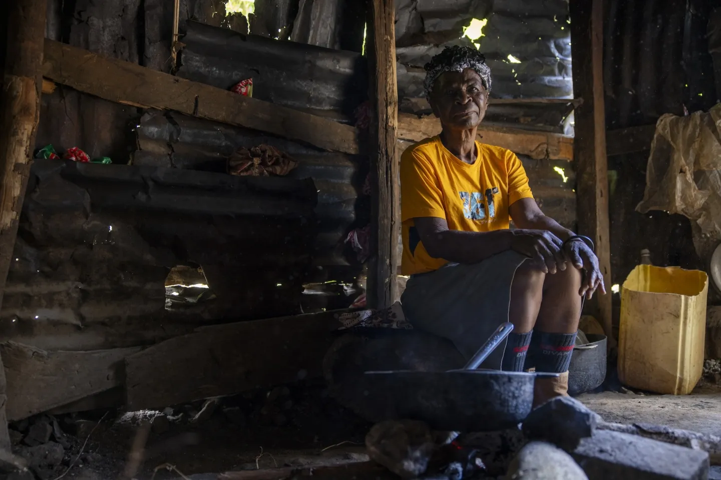 older person sitting inside home in front of stove in Haiti