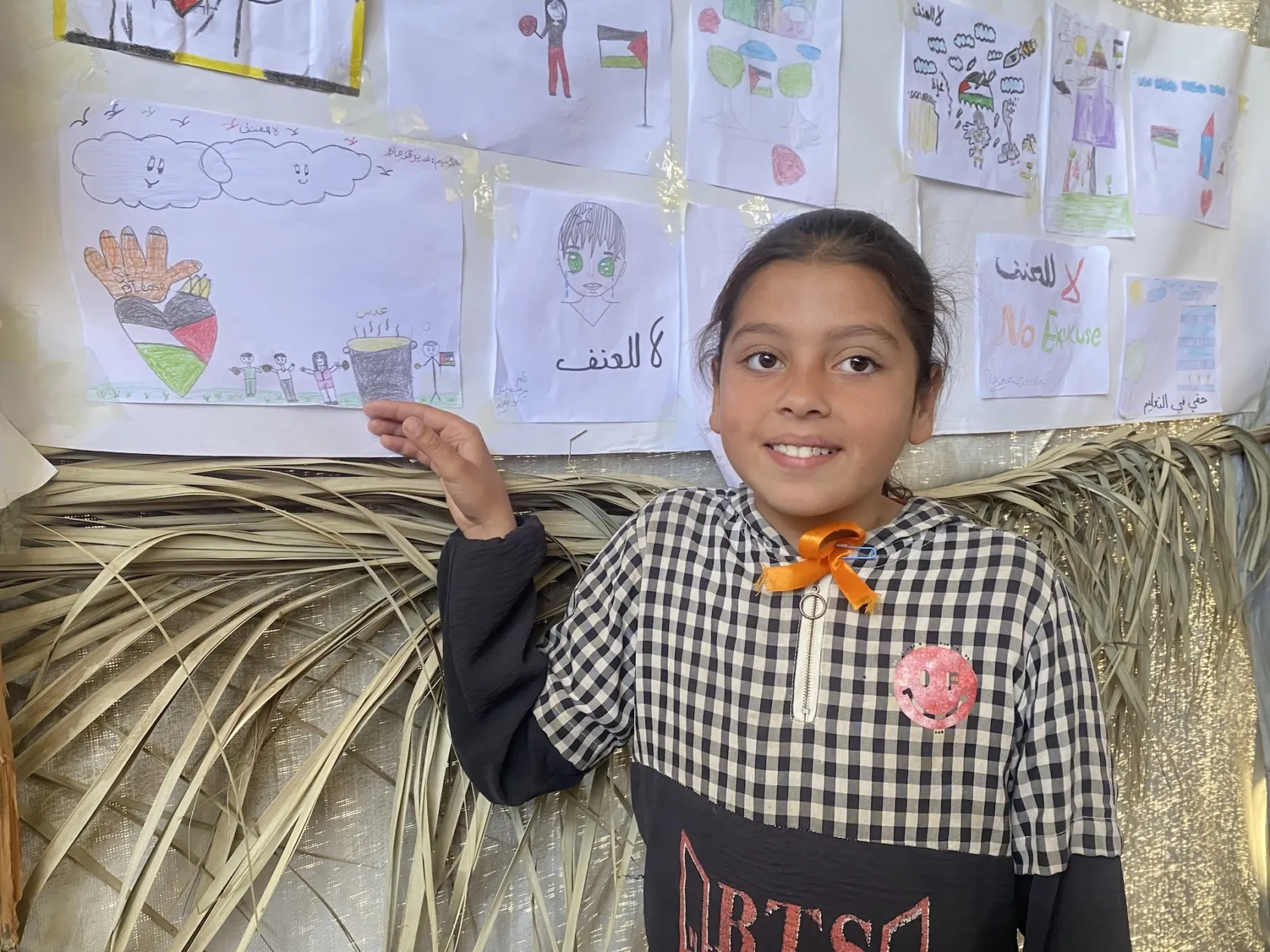 young girl shows artwork in Gaza camp