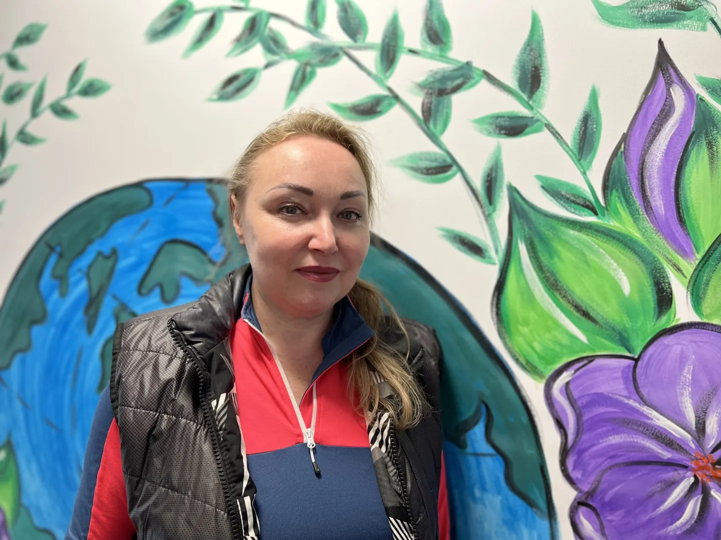 woman standing in front of mural of earth