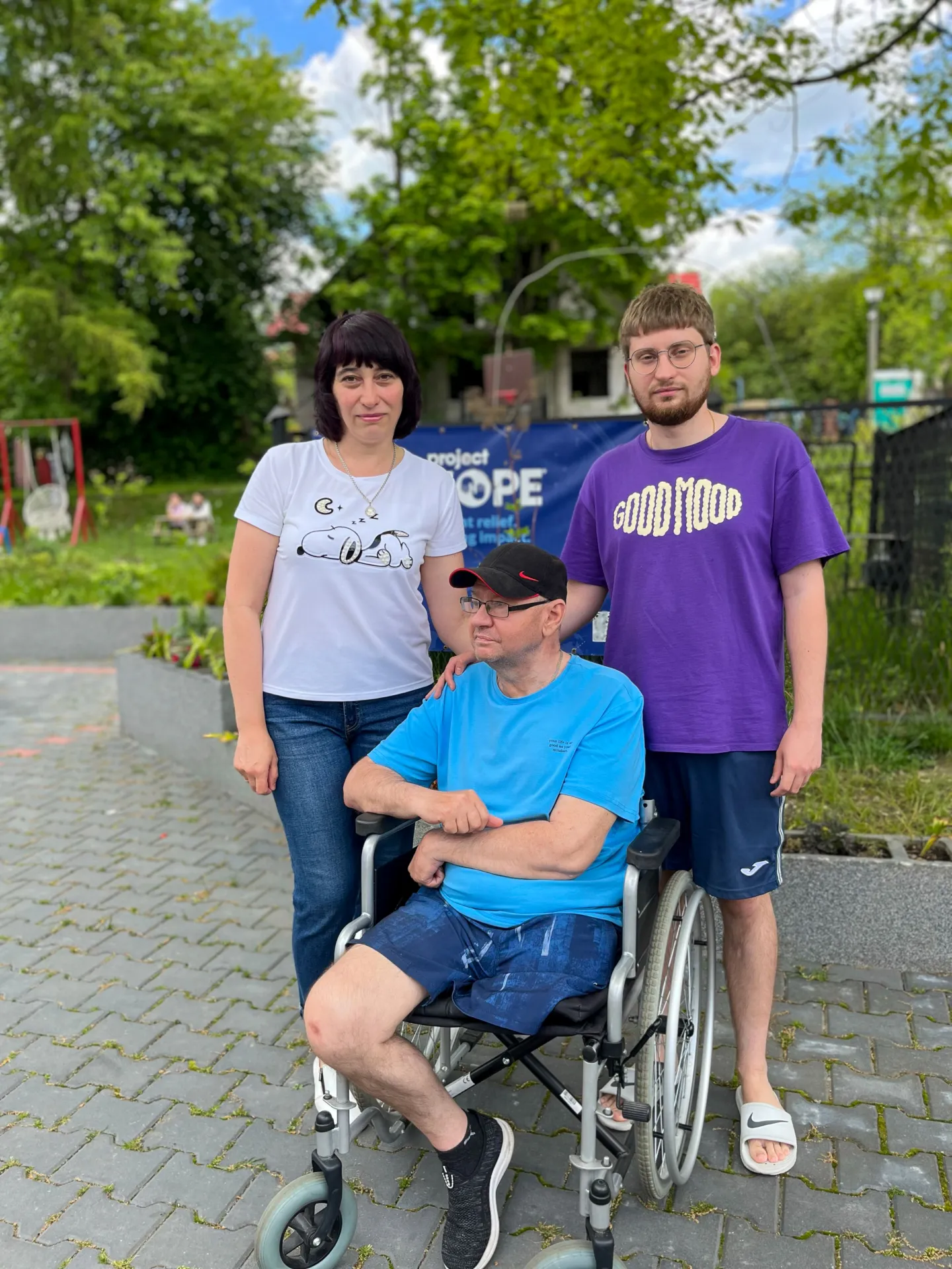 four people standing together with one in a wheelchair