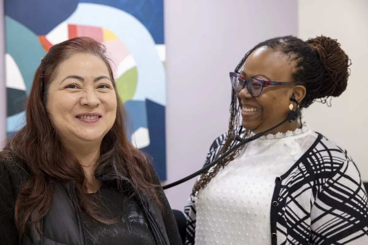 Two women at a medical facility. One is listening to the lungs of the other