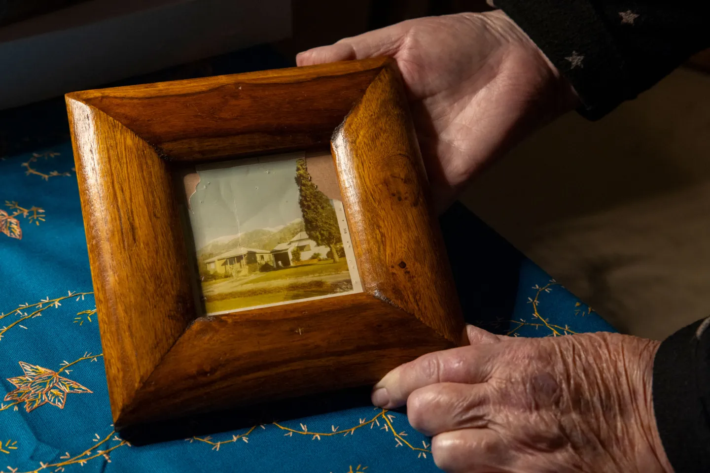 close up photo of a woman showing a picture of her home within a wooden frame