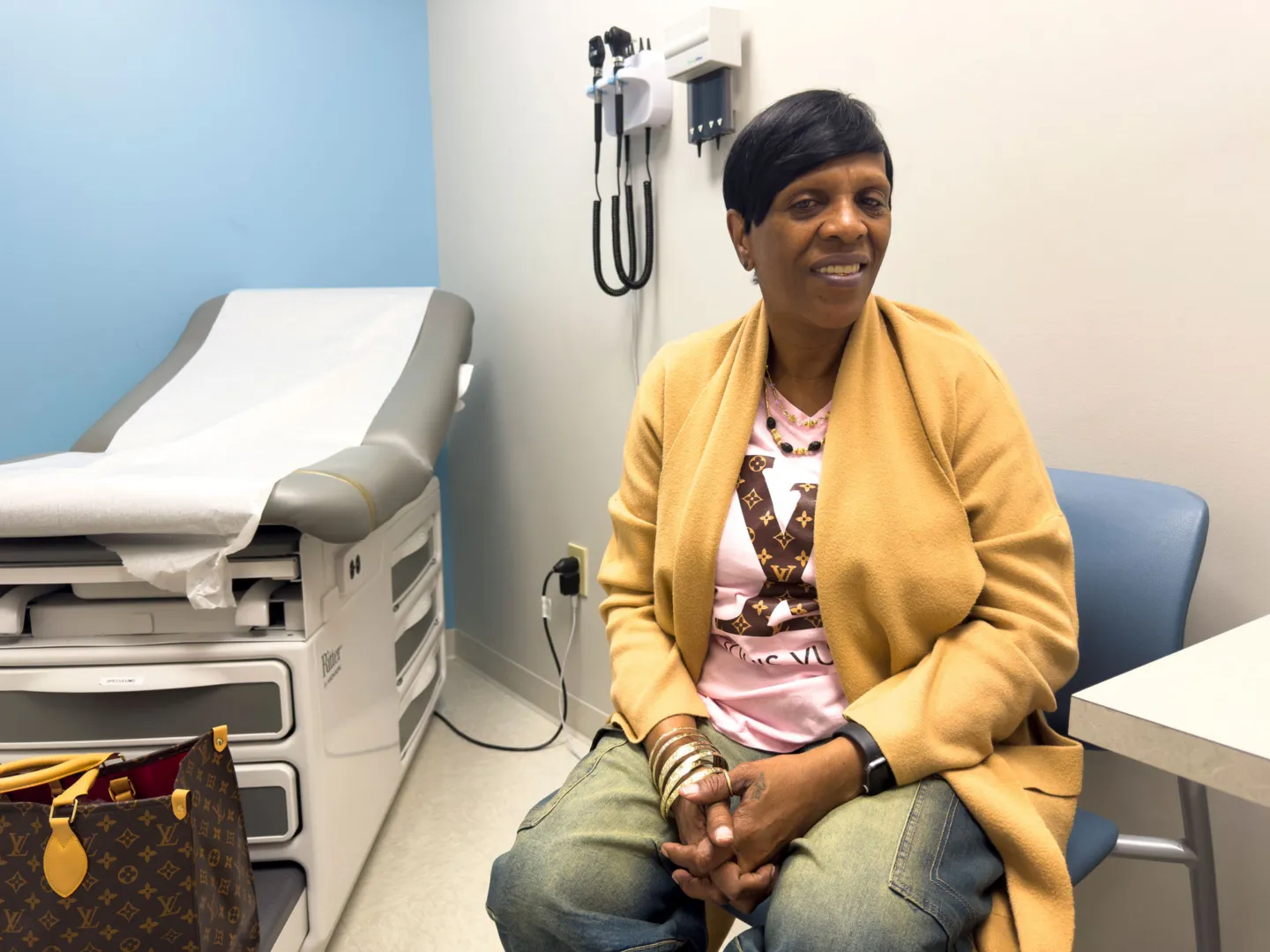 woman in yellow jacket sits inside doctor's office ahead of mammogram