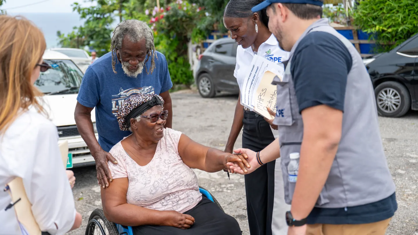 elderly couple, with one in a wheelchair, speak with Project HOPE staff in Jamaica