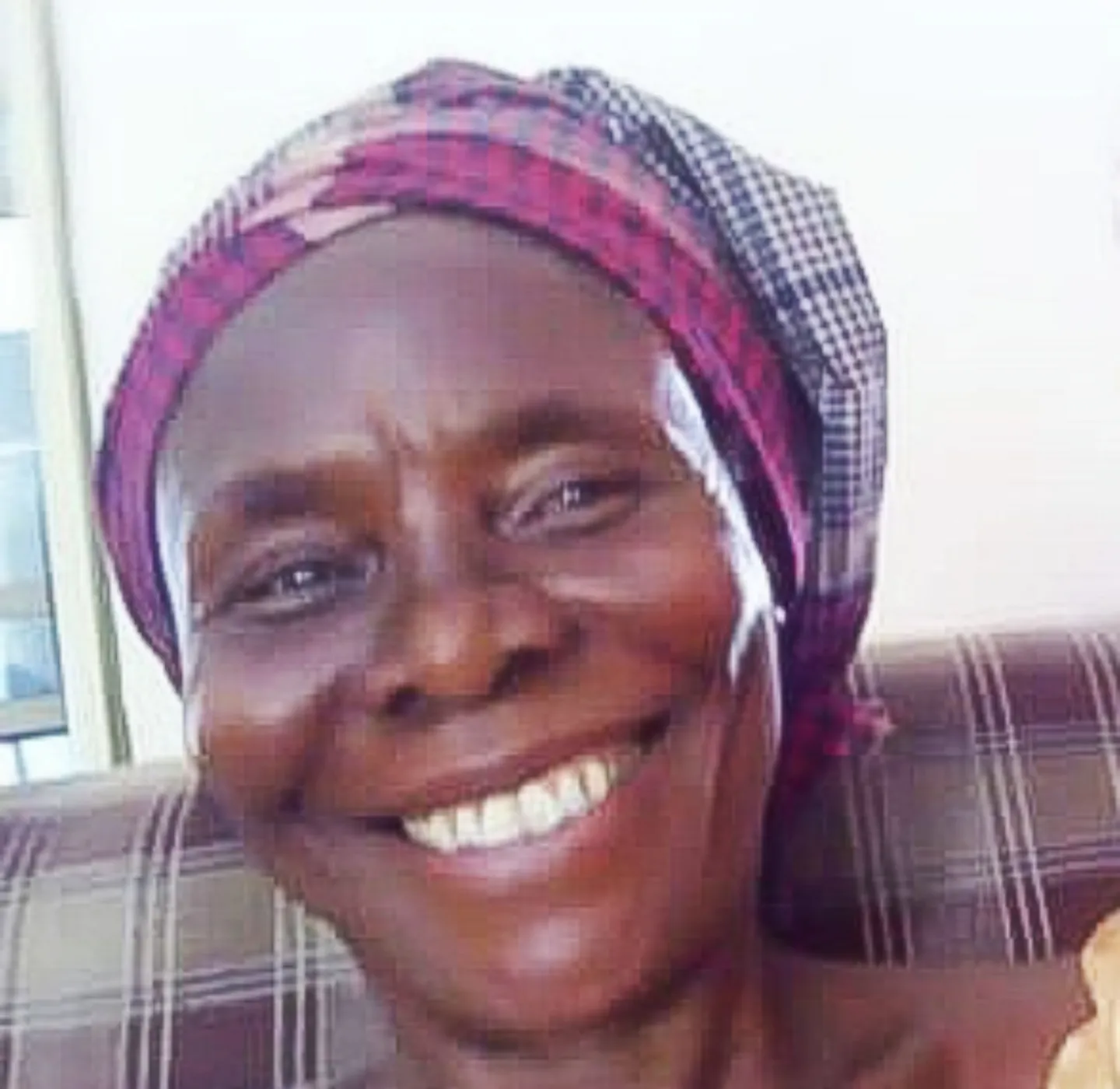 smiling woman wearing a scarf around her head.