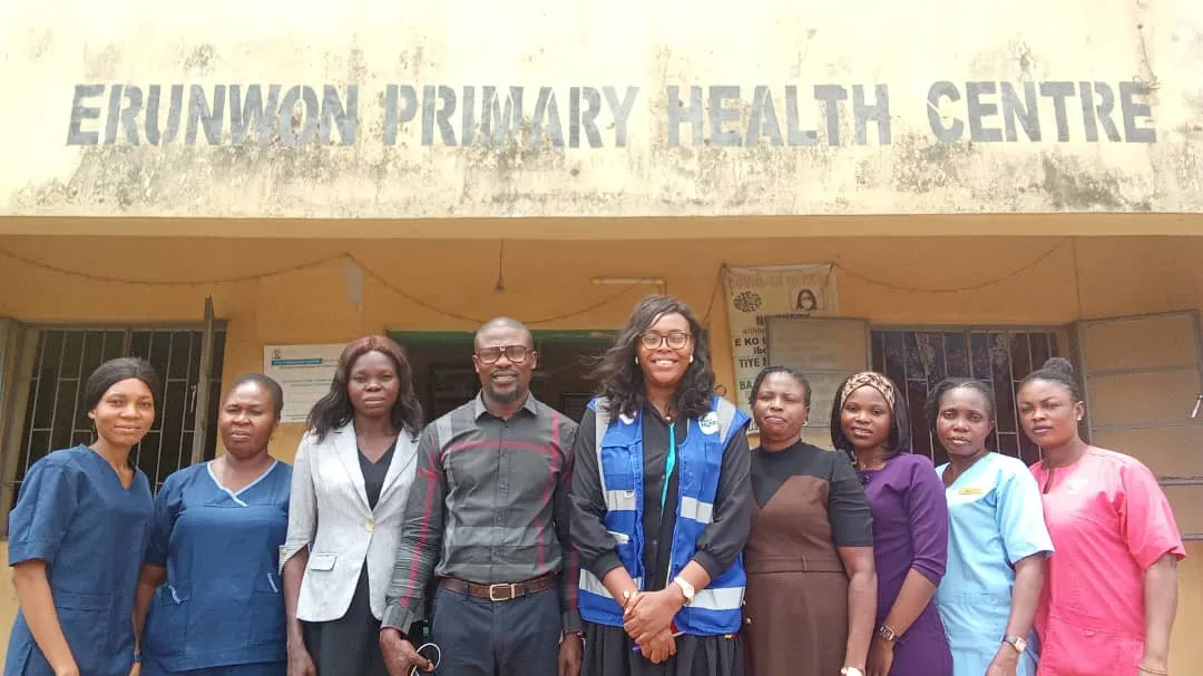 nine people standing in front of a health center in Nigeria. Four are nurses, four are administrative staff, and one Project HOPE staff member.