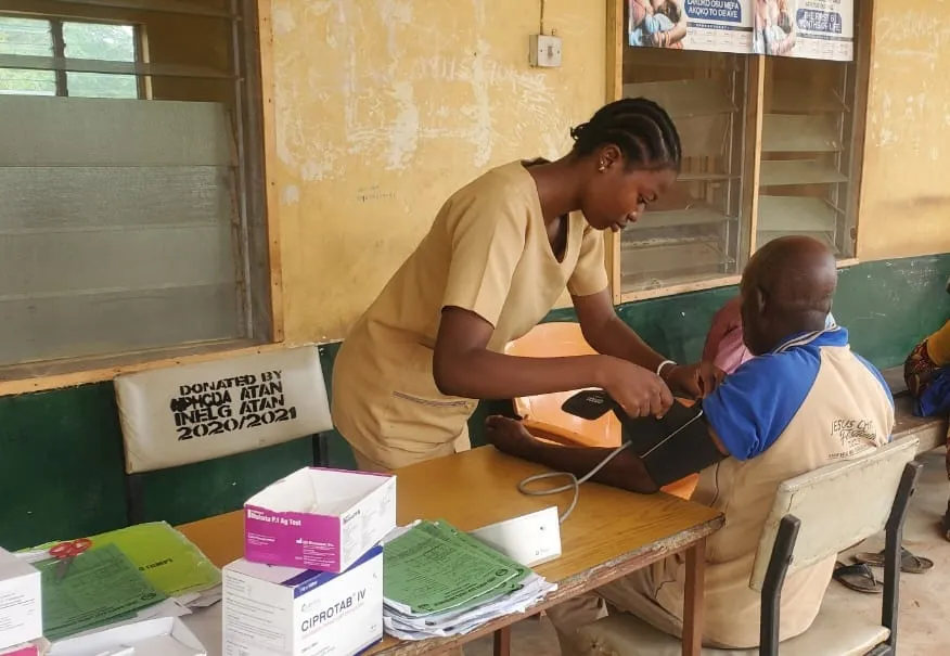 a medical staffer takes the blood pressure of a patient in Nigeria