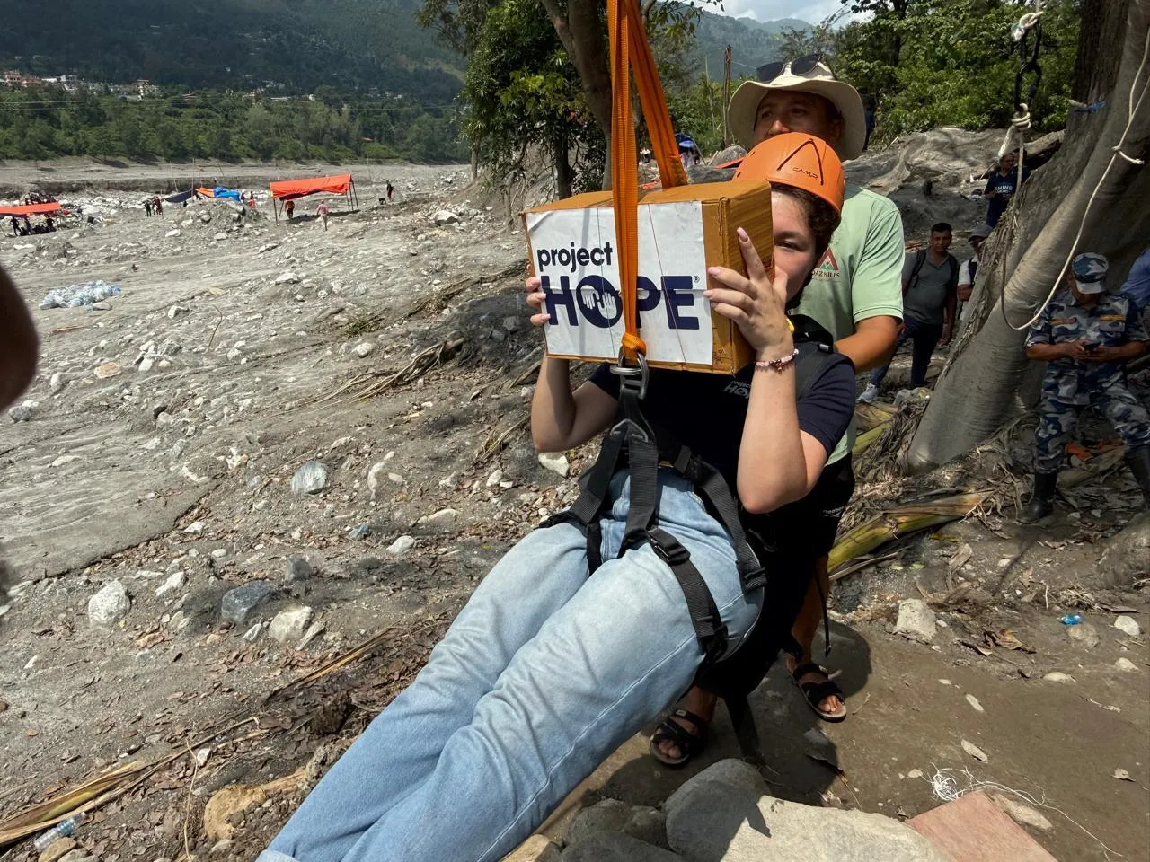 woman carries Project HOPE medicine across flooded river in Nepal.