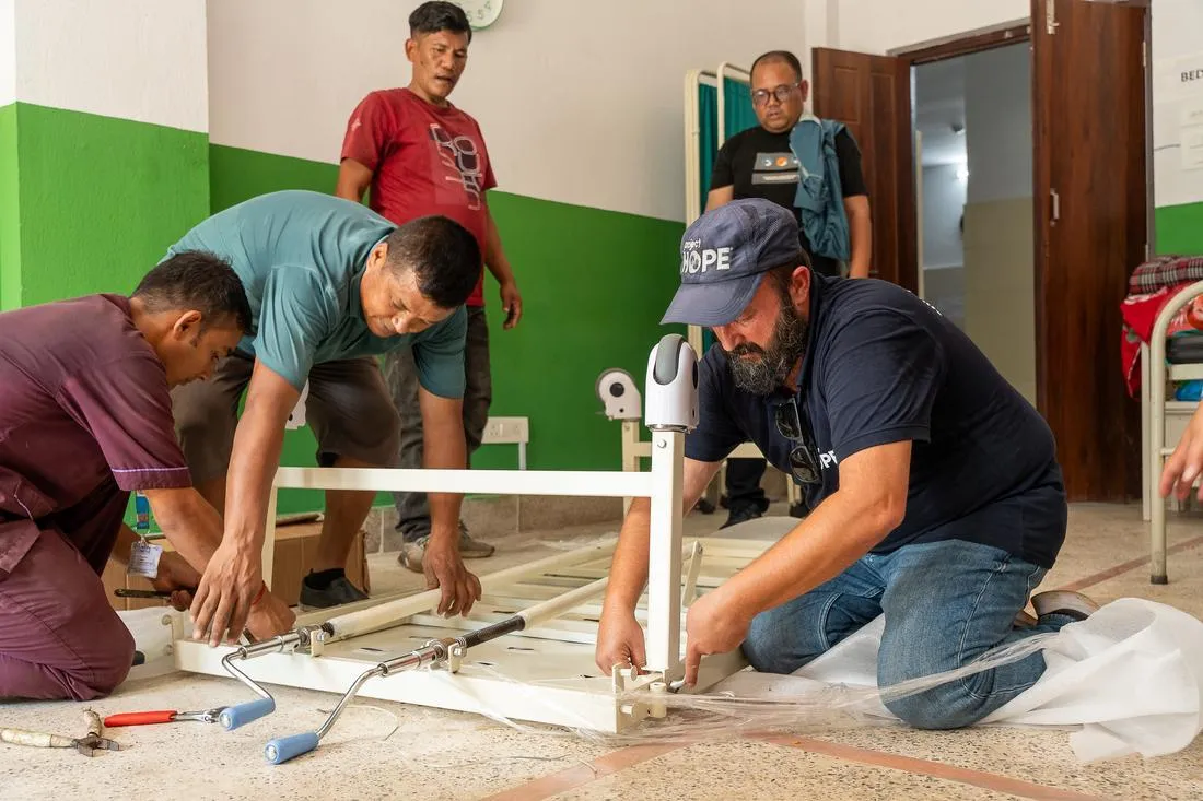 Project HOPE staff member helps Nepalese community members build hospital beds