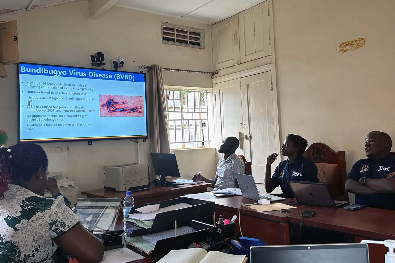 A group of people review a powerpoint on a large projection screen on Ebola to present to larger group.