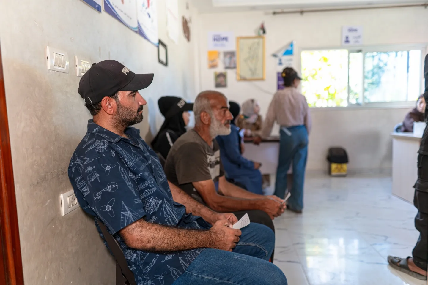 man waits in clinic waiting area for medication