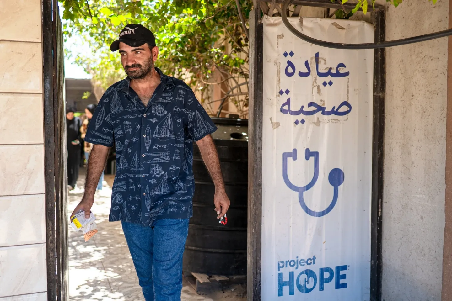 man walks through clinic carrying medication.