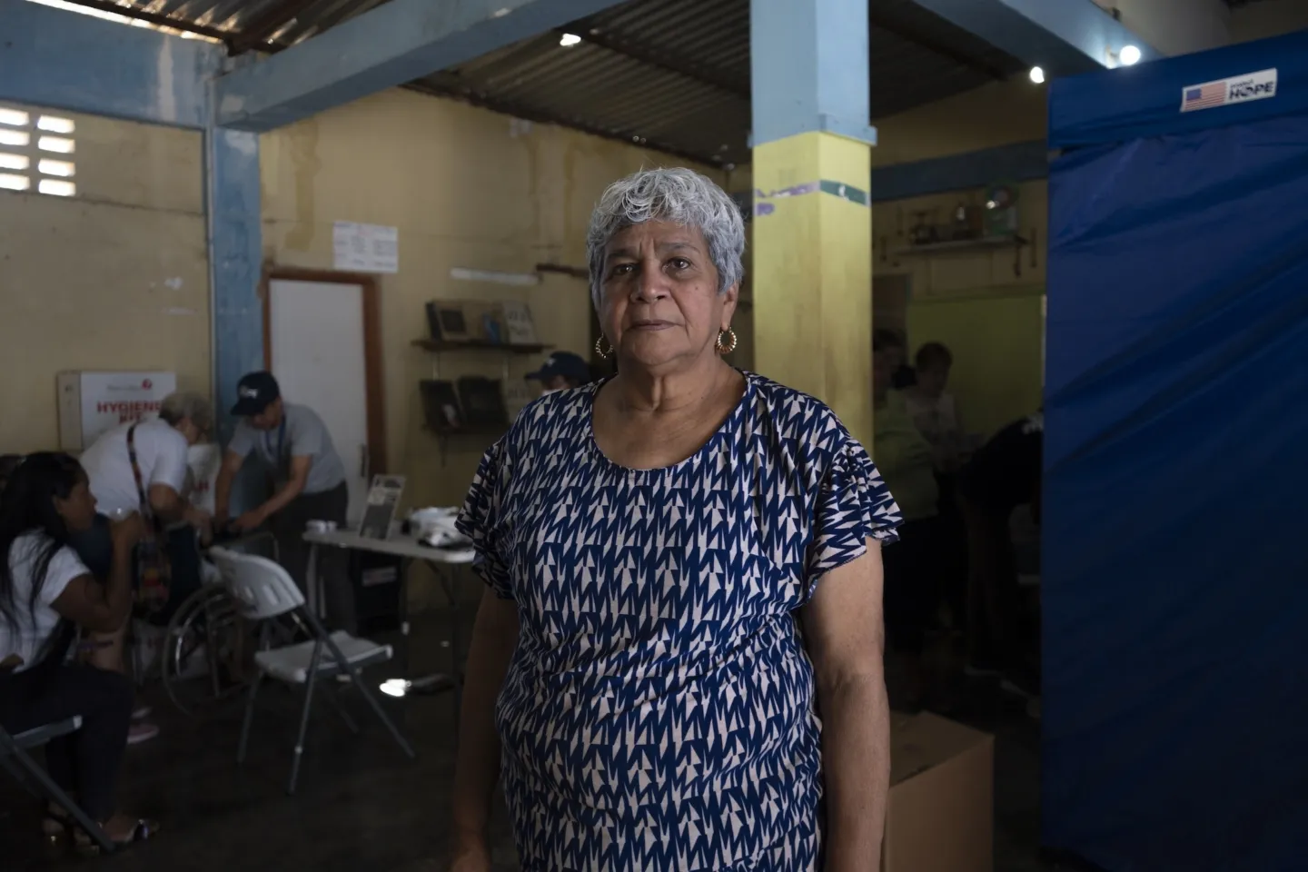 older woman in patterned blue shirt stands inside medical clinic in Venezuela