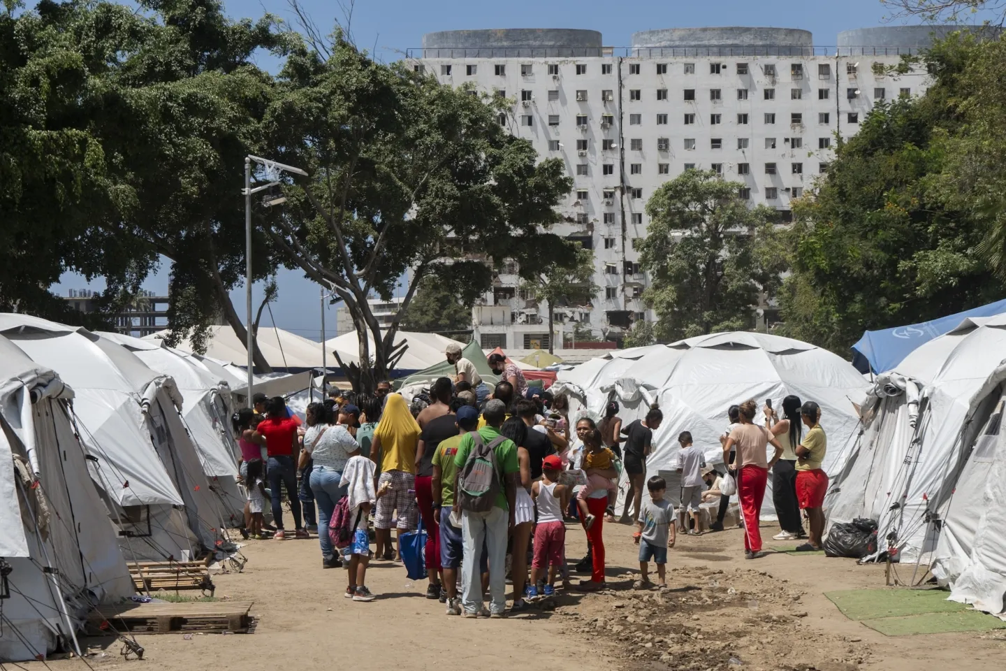 wide shot of groups of people standing within circle of raised tents seeking shelter post-earthquake in Venezuela
